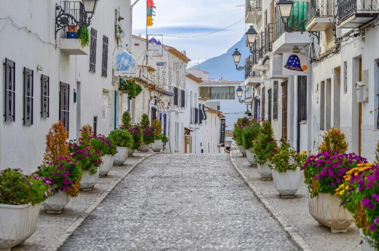 Picturesque alley in Altea, Spain, adorned with vibrant flowers and whitewashed buildings.