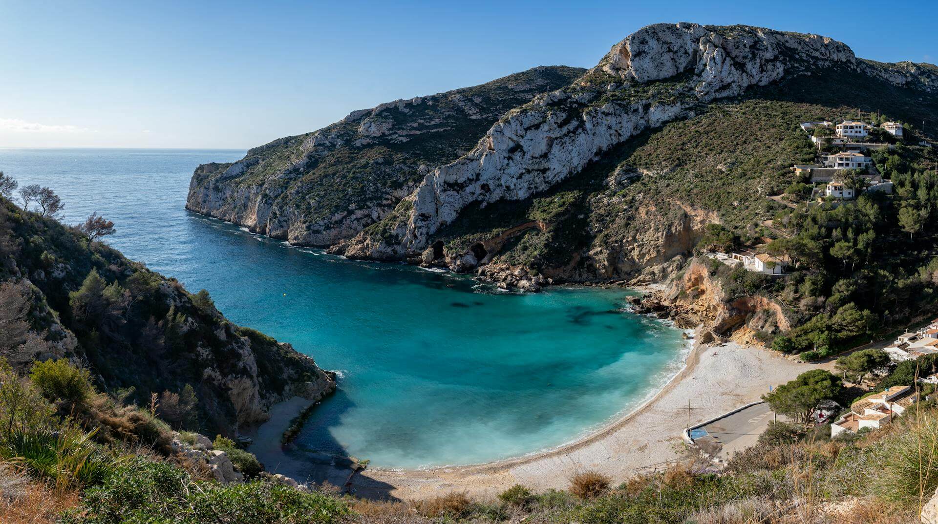 Crystal-clear turquoise waters and rocky cliffs at a hidden cove beach on the Costa Blanca, Spain.