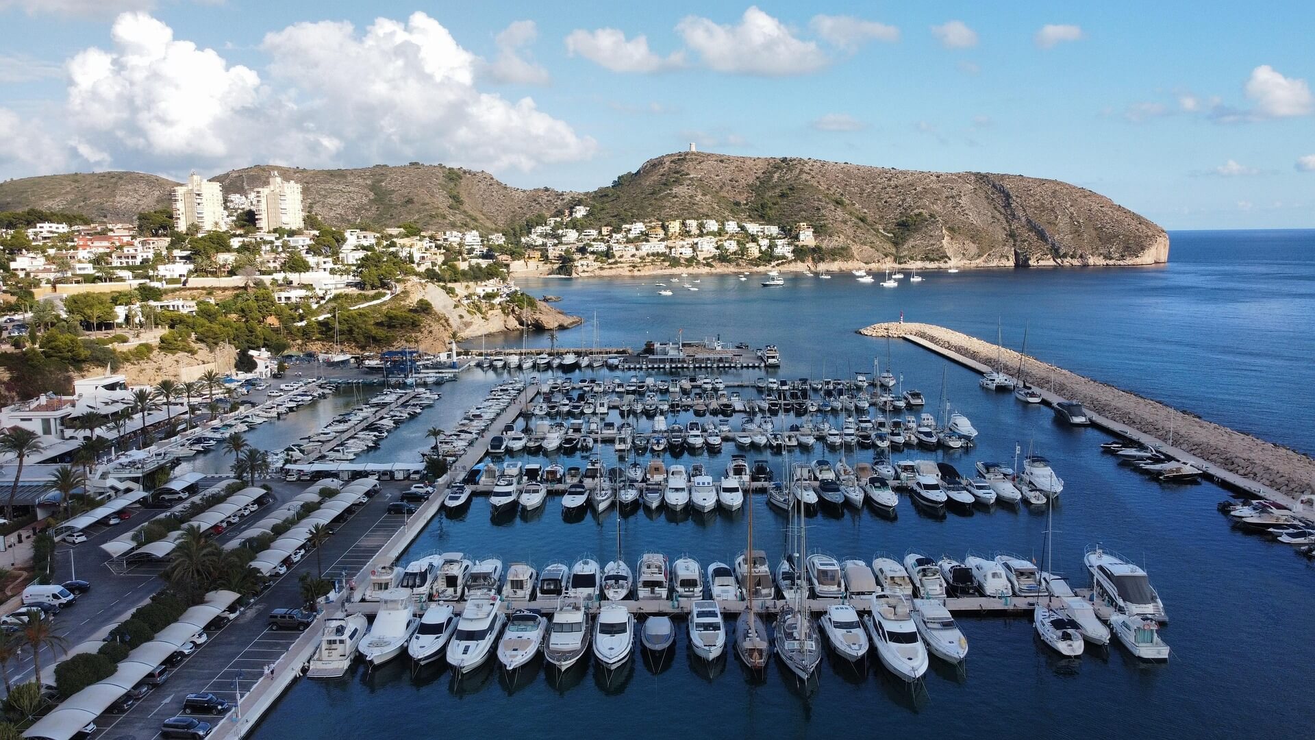 View of Moraira Marina and harbor on Costa Blanca, Spain, with yachts docked and Mediterranean waterfront.