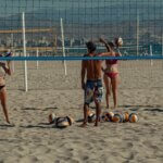 Beach volleyball players on San Juan Beach in Alicante, Spain, playing under the Mediterranean sun.