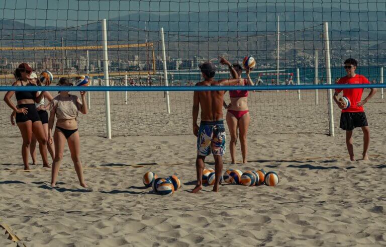 Beach volleyball players on San Juan Beach in Alicante, Spain, playing under the Mediterranean sun.