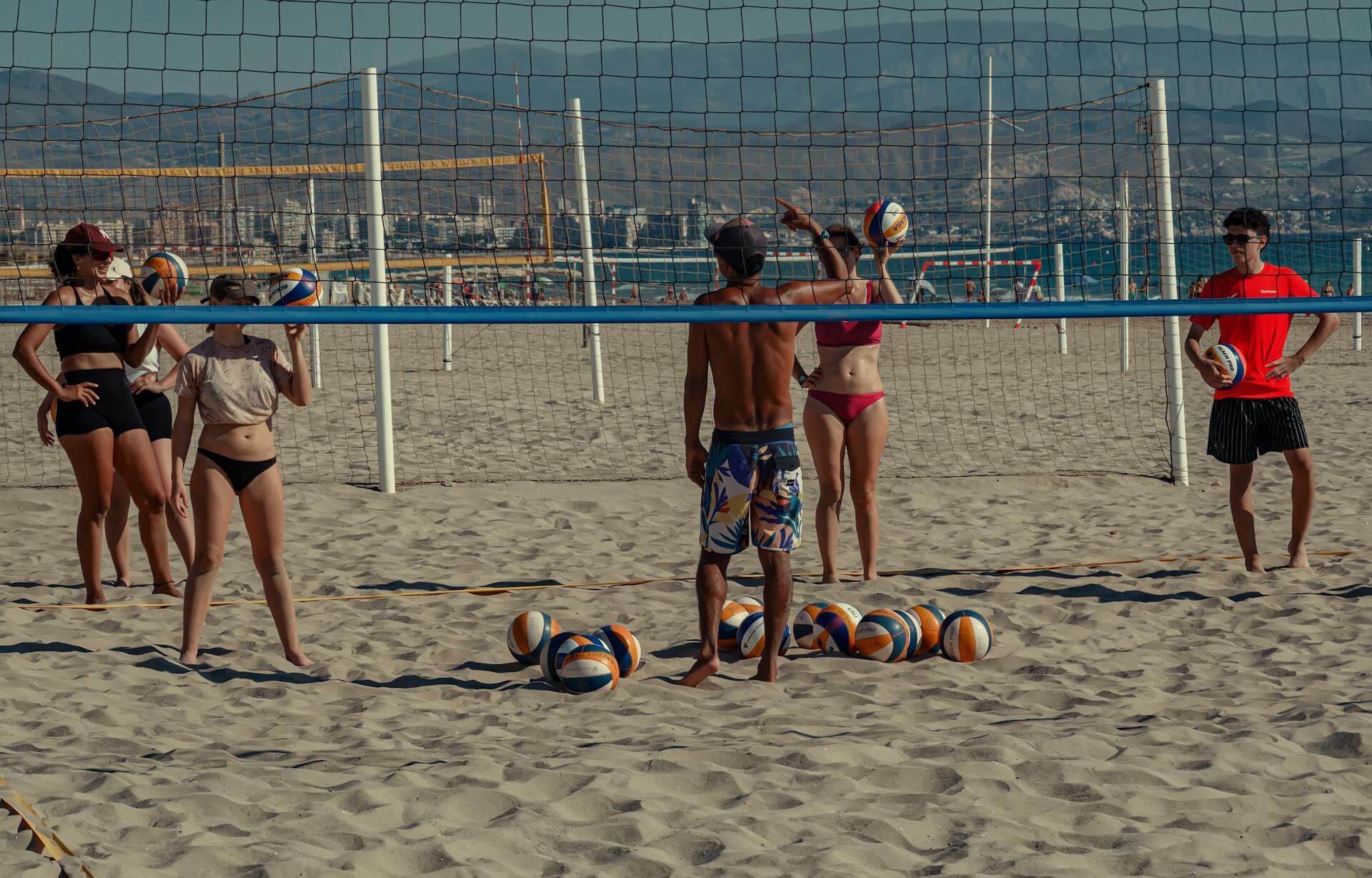 Beach volleyball players on San Juan Beach in Alicante, Spain, playing under the Mediterranean sun.