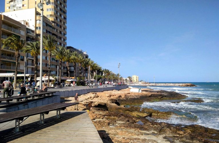 A vibrant view of Torrevieja's seafront promenade and beach on a sunny day, ideal for summer travel concepts.